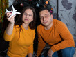 © Natali Mali - A woman holds a toy airplane in her hands and looks at it. A man sitting next to him looks at the toy. There is a Christmas tree behind. Selective focus.