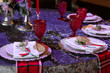 The table is served with red glasses. The plate is decorated with flowers