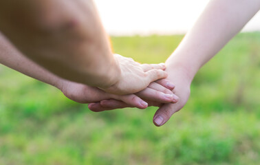 Close-up of young people putting their hands together. Friends holding hands show solidarity and teamwork.
