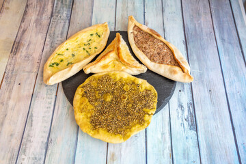 Plate with several different types of cheese fatayer, with minced lamb, Lebanese manakish, and meat and vegetables