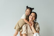 canvas print picture - cheerful asian toddler daughter hugging happy mother isolated on gray
