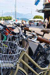 Wall Mural - Vertical shot of bicycles parked next to each other and background of a city life