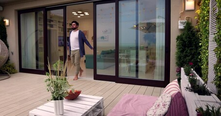 Wall Mural - man opens wooden sliding doors, going out on rooftop patio with cozy lounge zone