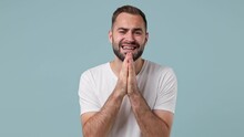 Pleading Begging Young Brunet Man 20s Wears White T-shirt Hold Hands Folded In Prayer Making Wish Keep Fingers Crossed Isolated On Pastel Light Blue Background. People Emotions Lifestyle Concept