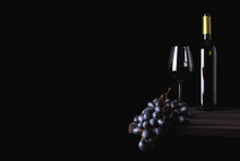 A Glass Of Red Wine, A Bottle And Grapes On A Dark Background. Free Space For Text. Alcoholic Beverage