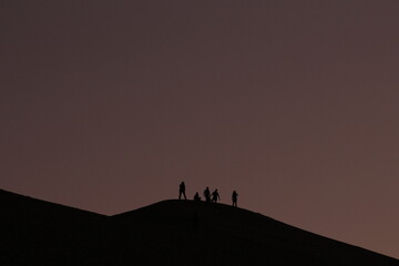 Atardecer en el desierto con silueta de personas