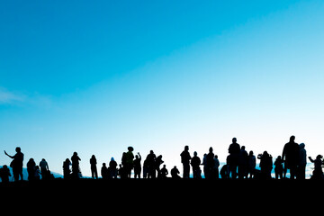 Silhouettes of tourist crowd waiting for the sunrise and doing activity, taking a photo, selfie with nature on the hill at viewpoint