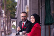 © PAPALAH - businessman caucasian and businesswoman Muslim working outdoor in the front of a coffee shop.