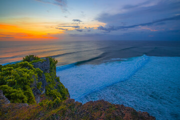 Wall Mural - Seascape. Spectacular view from Uluwatu cliff in Bali. Sunset time. Blue hour. Ocean with motion foam waves. Waterscape for background. Nature concept. Soft focus. Slow shutter speed.