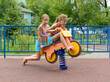 Tween caucasian girls sits on toy wooden motorbike on playground