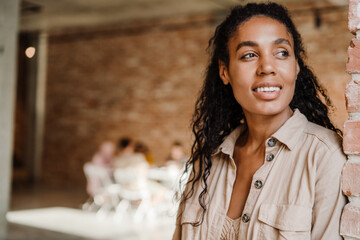 Black young woman smiling while leaning on wall