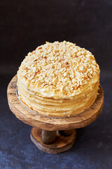 Sticker - Cake on a wooden cake plate. Shortcrust pastry cake, multilayer cake, decorated with shortcrust crumbs on top. Blue background, side view.