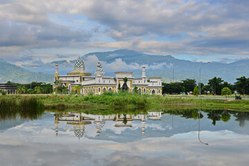 Temple, hills, and cloudy sky reflected in a lake