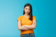 Serious-looking indifferent and upset intense asian woman brunette, cross arms chest look strict ignorant, pissed listening nonsense, annoyed stupid conversation, stand blue background