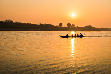 Wall Mural - Fishermen in the boat on sunrise background