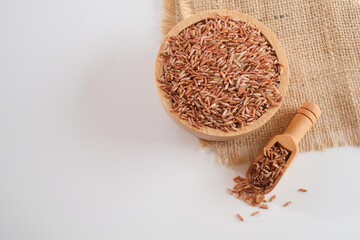 Wall Mural - Wooden bowl and wooden scoop of Germinated Sangyod brown GI Muang Phatthalung rice on the sackcloth over wooden table background. Healthy food. Top view. Flat lay. 