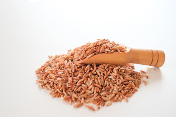 Wall Mural - Wooden scoop of Germinated Sangyod brown GI Muang Phatthalung rice on the pile of rice isolated on white background. Healthy food.This rice nose have lot of various kinds of nutrients.