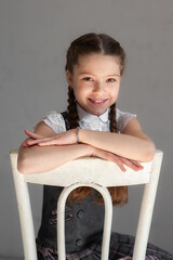 Wall Mural - Little schoolgirl sitting on chair.