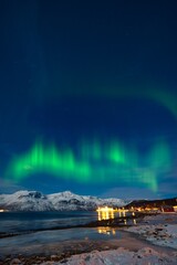 northern lights over the snow capped mountains in the night in the arctic area of norway