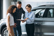 © Petro - Young couple talking to a sales person in a car showroom