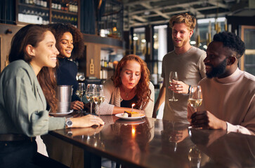 Wall Mural - Woman blowing out birthday candle in bar