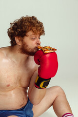 Wall Mural - Funny red-headed man in blue boxing shorts and gloves isolated on gray studio background. Concept of sport, humor and body positive.