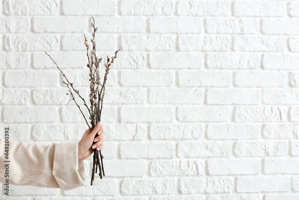 Woman holding willow branches near brick wall