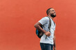 © ADDICTIVE STOCK - Smiling Black man with backpack looking up while standing outdoors