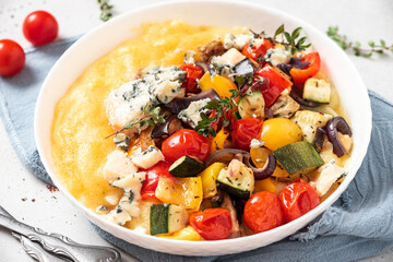 Wall Mural - Polenta with stewed vegetables and herbs in a bowl. Polenta with tomatoes, peppers, zucchini, eggplant and thyme. Italian cuisine, vegetarian food.