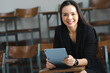 © mnirat - A middle-aged Asian woman teacher holding a tablet sitting in the classroom at University