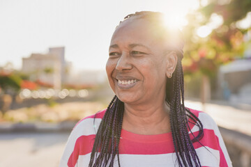 Senior african woman in the city with sunset in the background