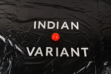 Words Indian Variant Laid With Silver Metal Letters On Crumpled Black Plastic Bag Background, Close-up With Small Virus Model