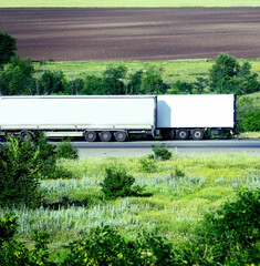 Two white container trucks on road.