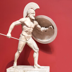 a stone sculpture of a Roman soldier with a spear and shield. The concept of strength, courage. Red background