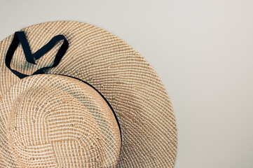 Wall Mural - Top view of a straw hat with black ribbon isolated on a light gray background