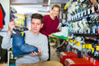 © JackF - Saleswoman is helping happy cheerful positive man to trying on boots for skiing in sport store.