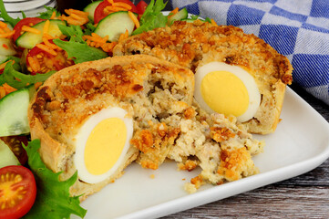 Wall Mural - Scotch egg quiche with shortcrust pastry and whole egg encased in pork sausage meat with fresh salad