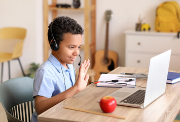 Wall Mural - Little African-American schoolboy studying online at home