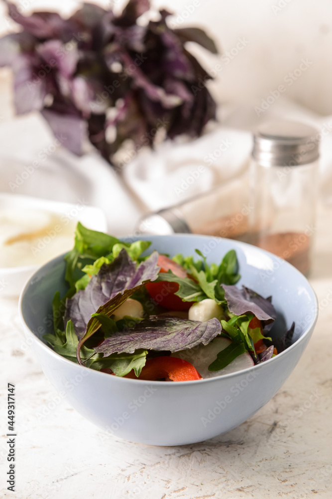 Bowl with tasty fresh salad on light background, closeup