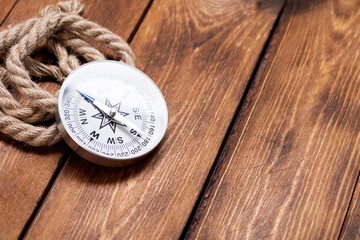 Wall Mural - Compass and rope on wooden texture background