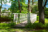 Fototapeta  - A white wooden bridge in the Poltsamaa city park (Estonian - Põltsamaa) on a sunny summer day.