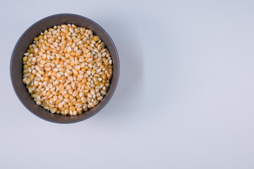 Sticker - Top view of corn grains on a bowl isolated on light gray background