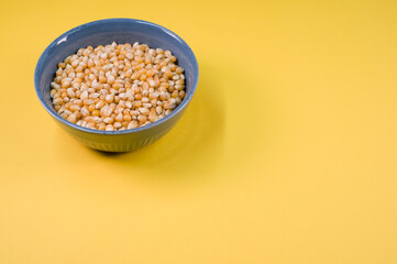 Poster - High angle shoof corn grains on a bowl isolated on yellow background