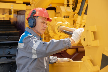 Professional mechanic checks hydraulic hose system equipment on excavator to raise bucket