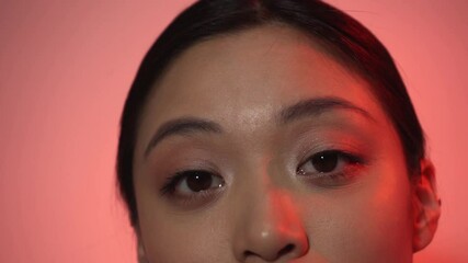 Wall Mural - cropped view of brunette asian woman looking at camera on pink