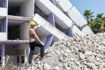 Wall Mural - Engineer standing on pile of collapsed building debris on demolish building.