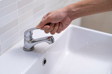 Wall Mural - The faucet in the bathroom with running water. Man keeps turning off the water to save water energy and protect the environment. save water concept