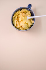 Sticker - Vertical shot of corn flakes on a cup with plastic spoon isolated on brbackground