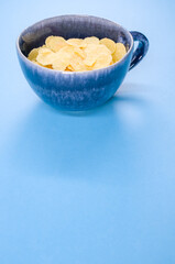 Sticker - Vertical shot of corn flakes on a cup isolated on blue background