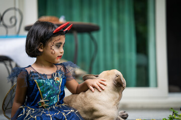 Wall Mural - Adorable girl in halloween costume sitting outdoor with her dog.